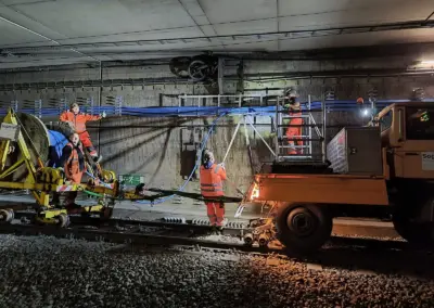 Ein Unimog der Firma Sogetrel steht in einem Bauhaustunnel, daneben sind Bauarbeiter beschäftigt, die Kabel verlegen